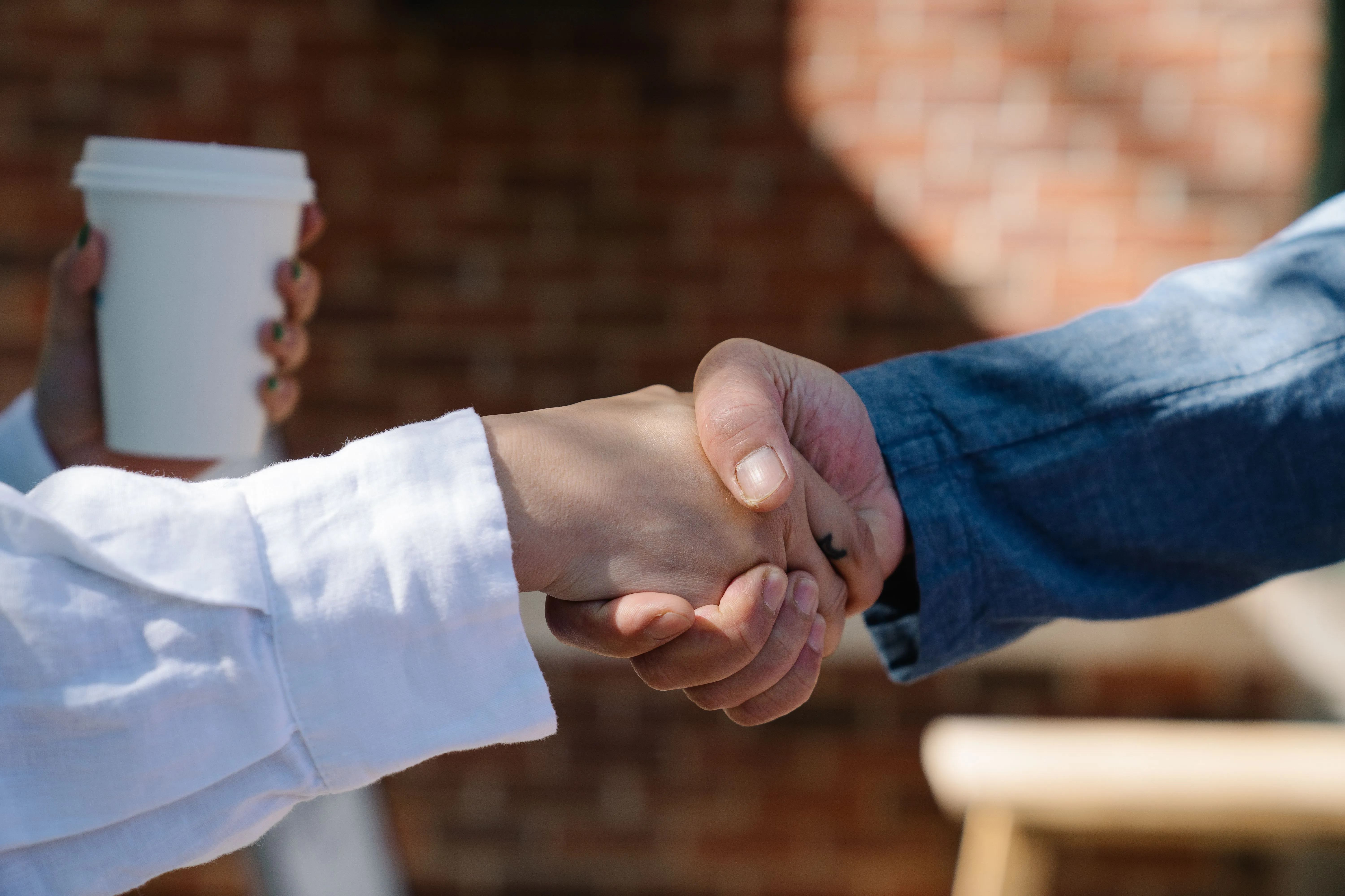 Two people shaking hands across a table.