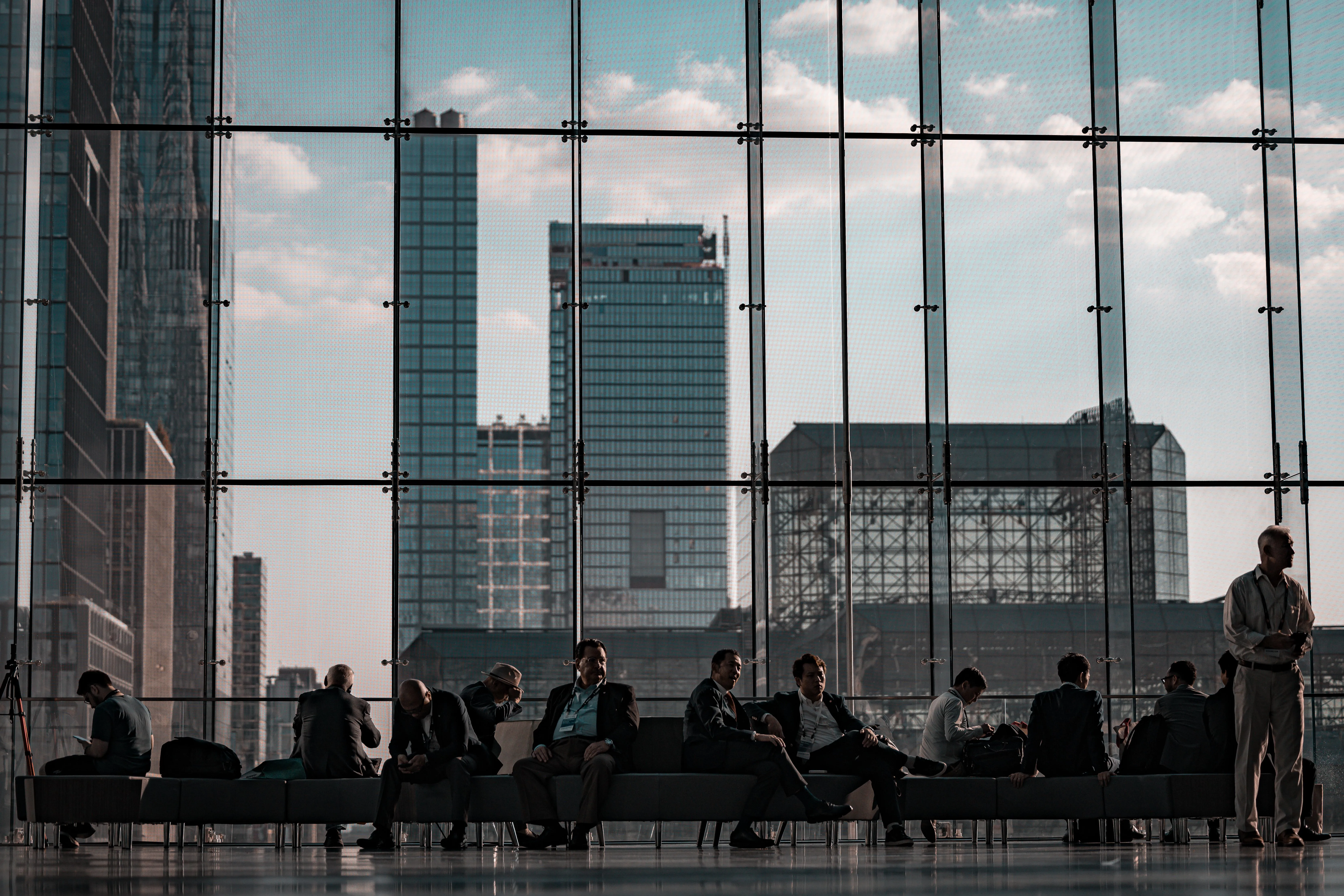 Figures silhouetted against a glazed wall above a city skyline.