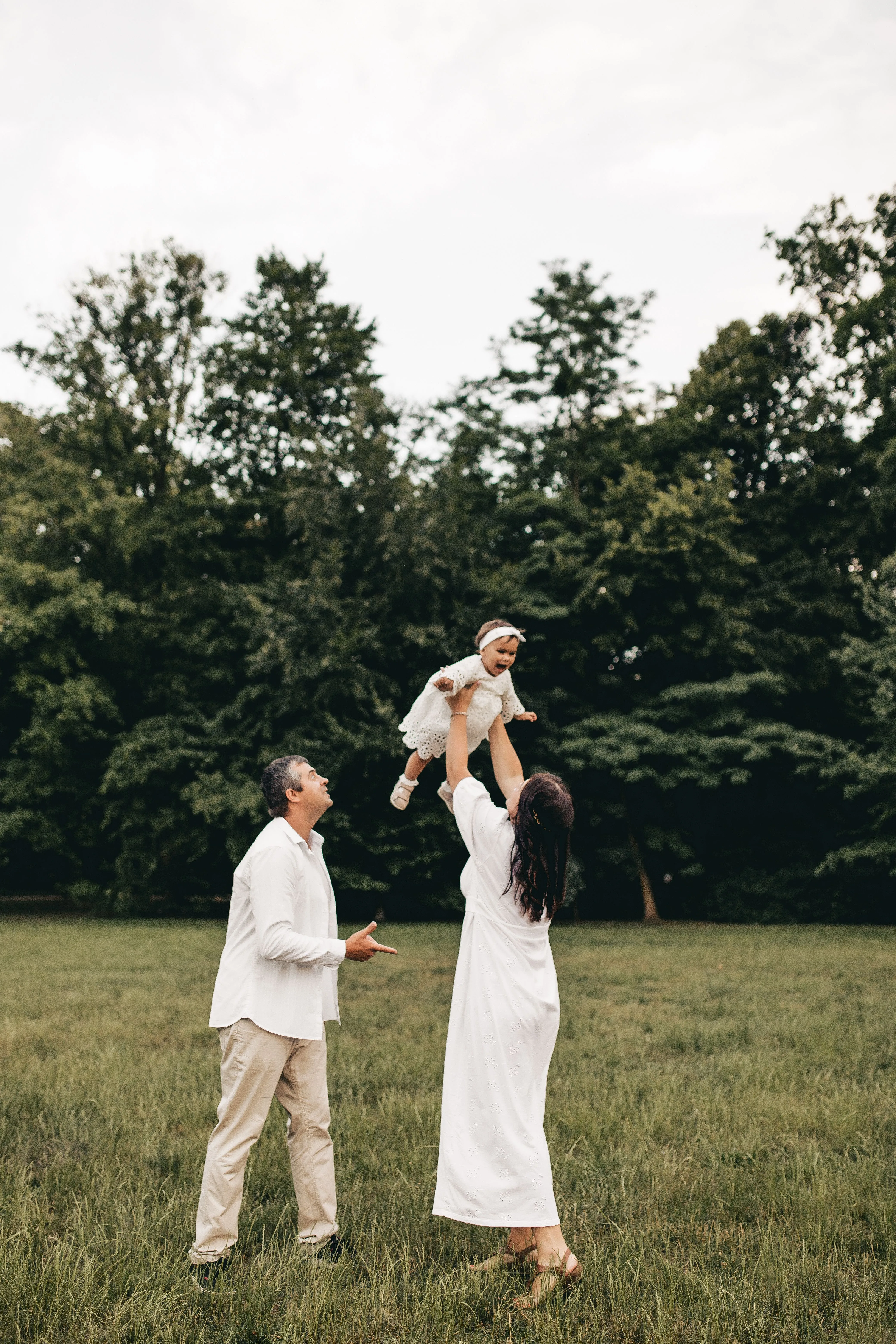 A family in white linen playing together on open grass.