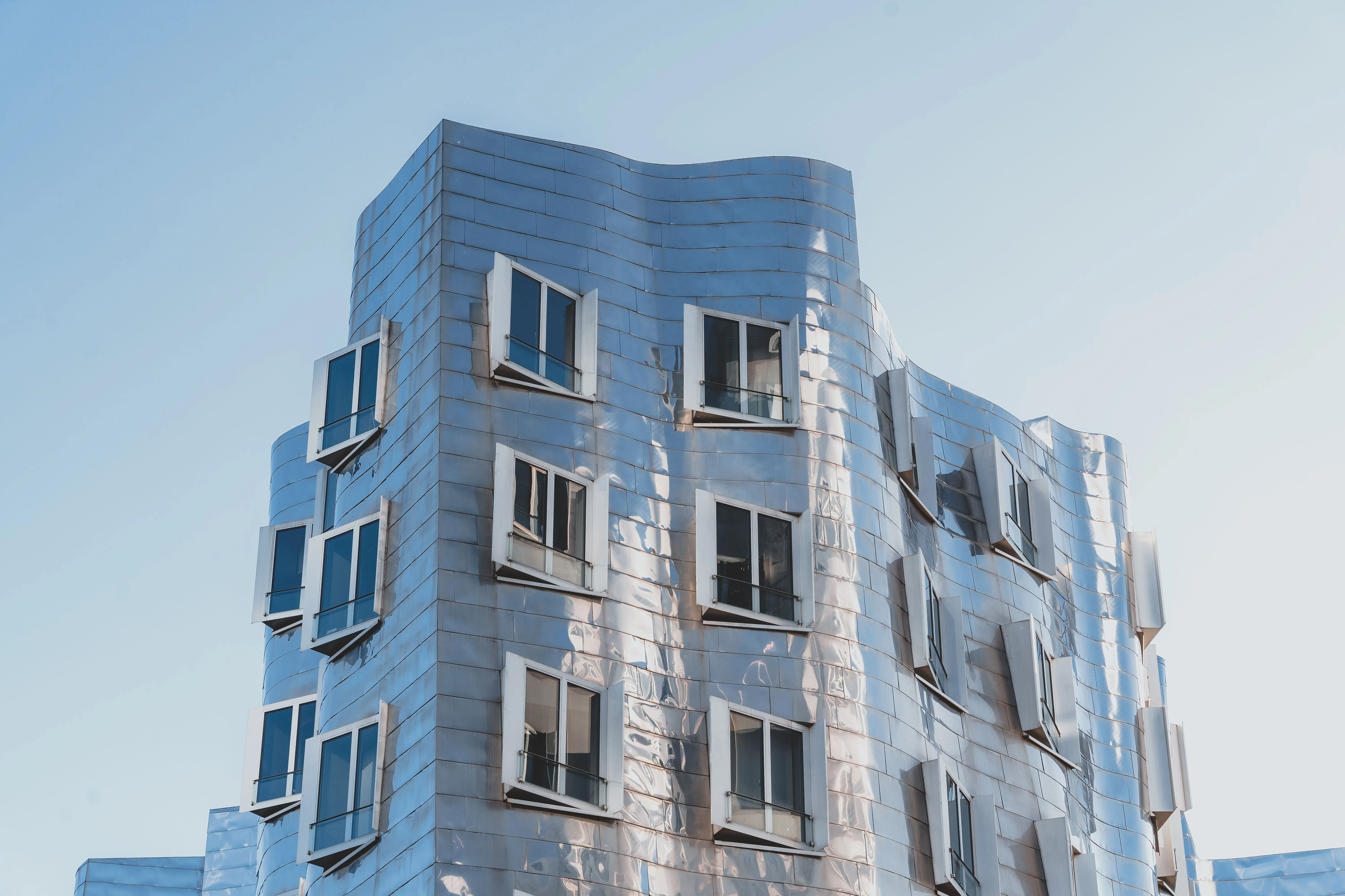A pale blue apartment building against clear sky.