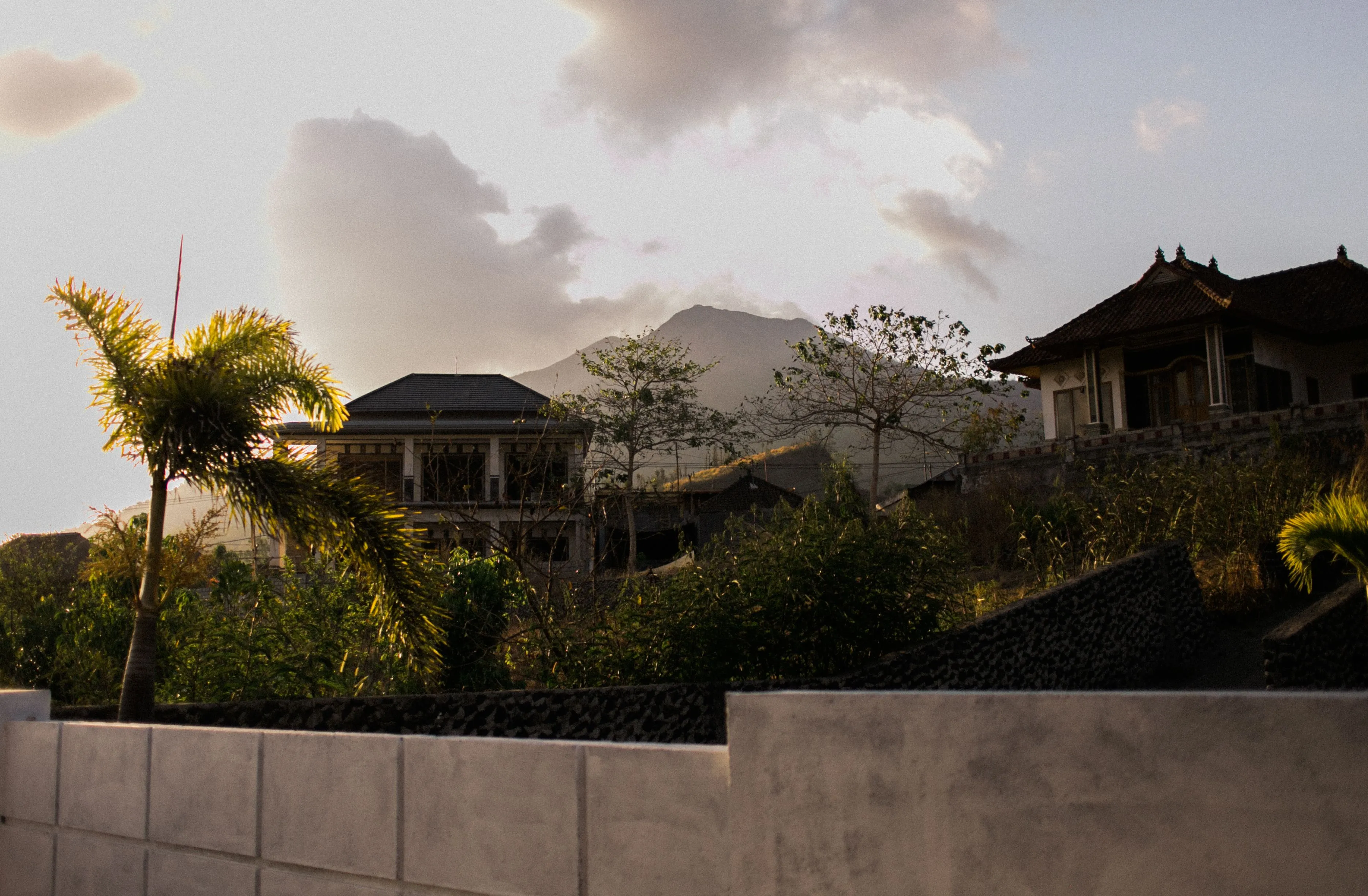 Villas set into a hillside with mountains behind at dusk.