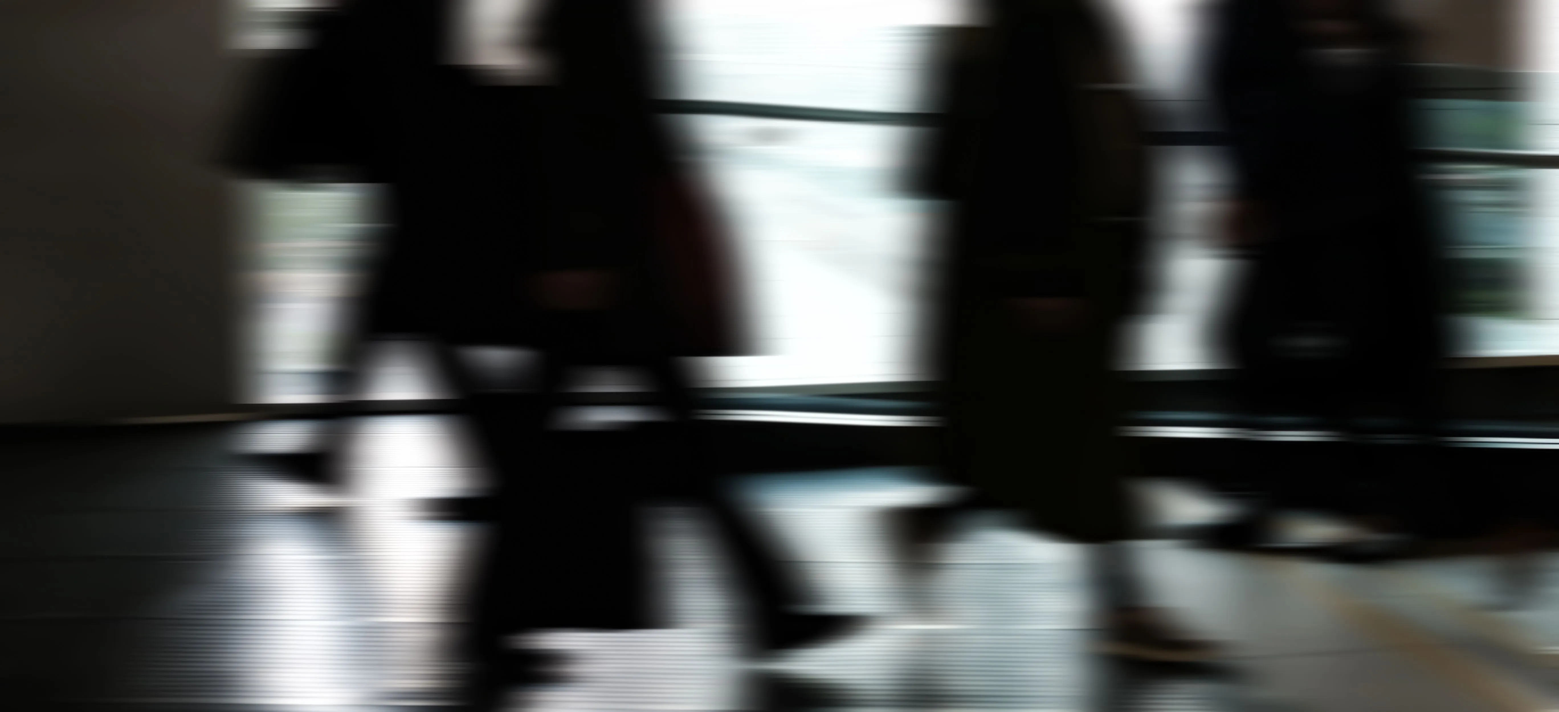 Figures crossing a concourse, caught in motion blur.