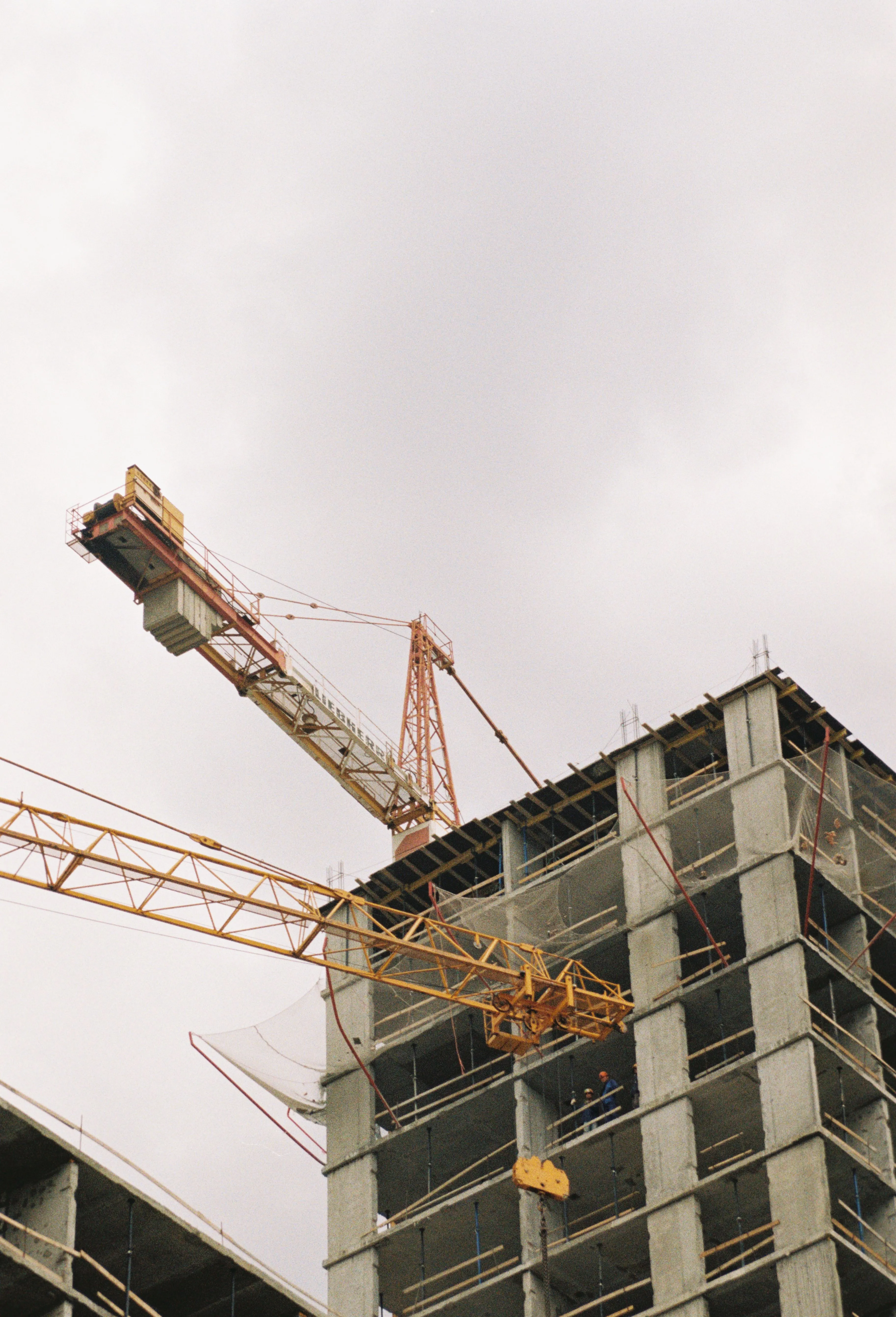 A tower crane above an unfinished concrete frame.